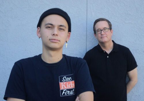 two men standing together wearing Sac Kids First t-shirts