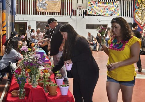 People taking food and drinks from a table at an event in a school auditorium