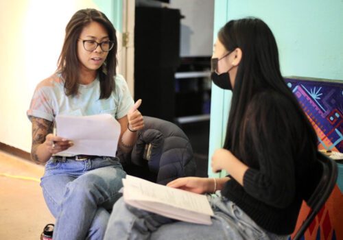 Two young ladies sitting on chairs talking together